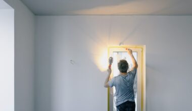 A man holding a light and finishing the paint job on his home's walls.
