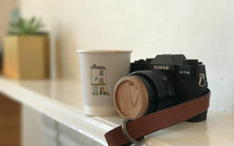 A camera and cup sitting on the mantle of someone's home.