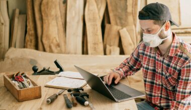 Man in dust mask sitting on a workbench using his laptop