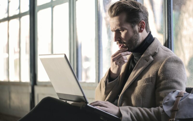 Professional man sitting on his laptop looking puzzled.