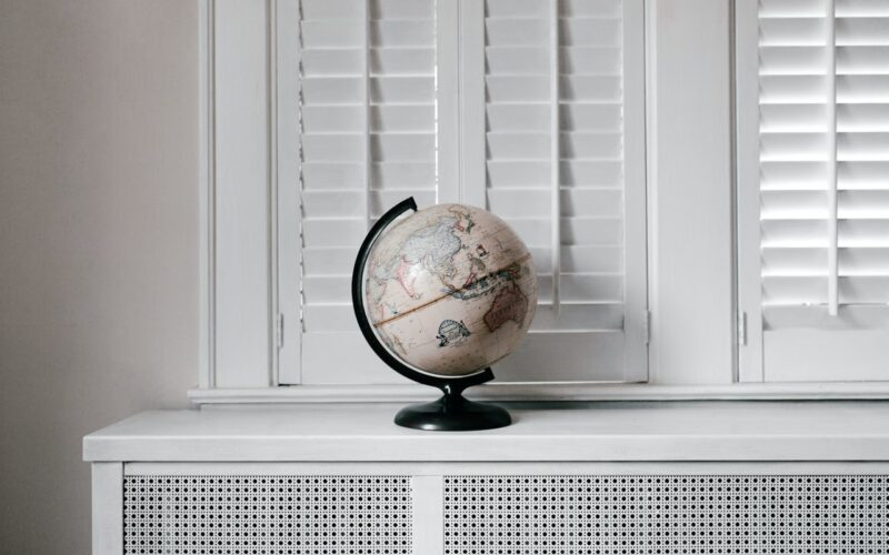 A globe sitting on a white desk behind windows.