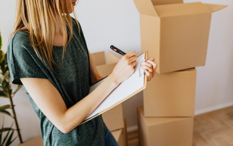 Woman signing paperwork with moving boxes in the background