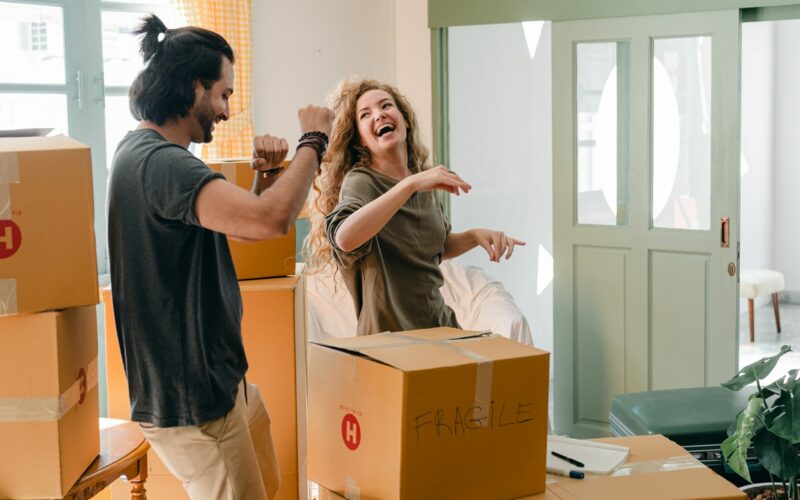 a man and woman dancing while packing boxes