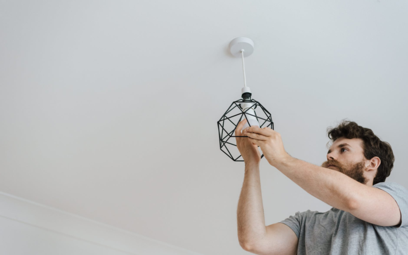 man with a beard screwing in a light bulb